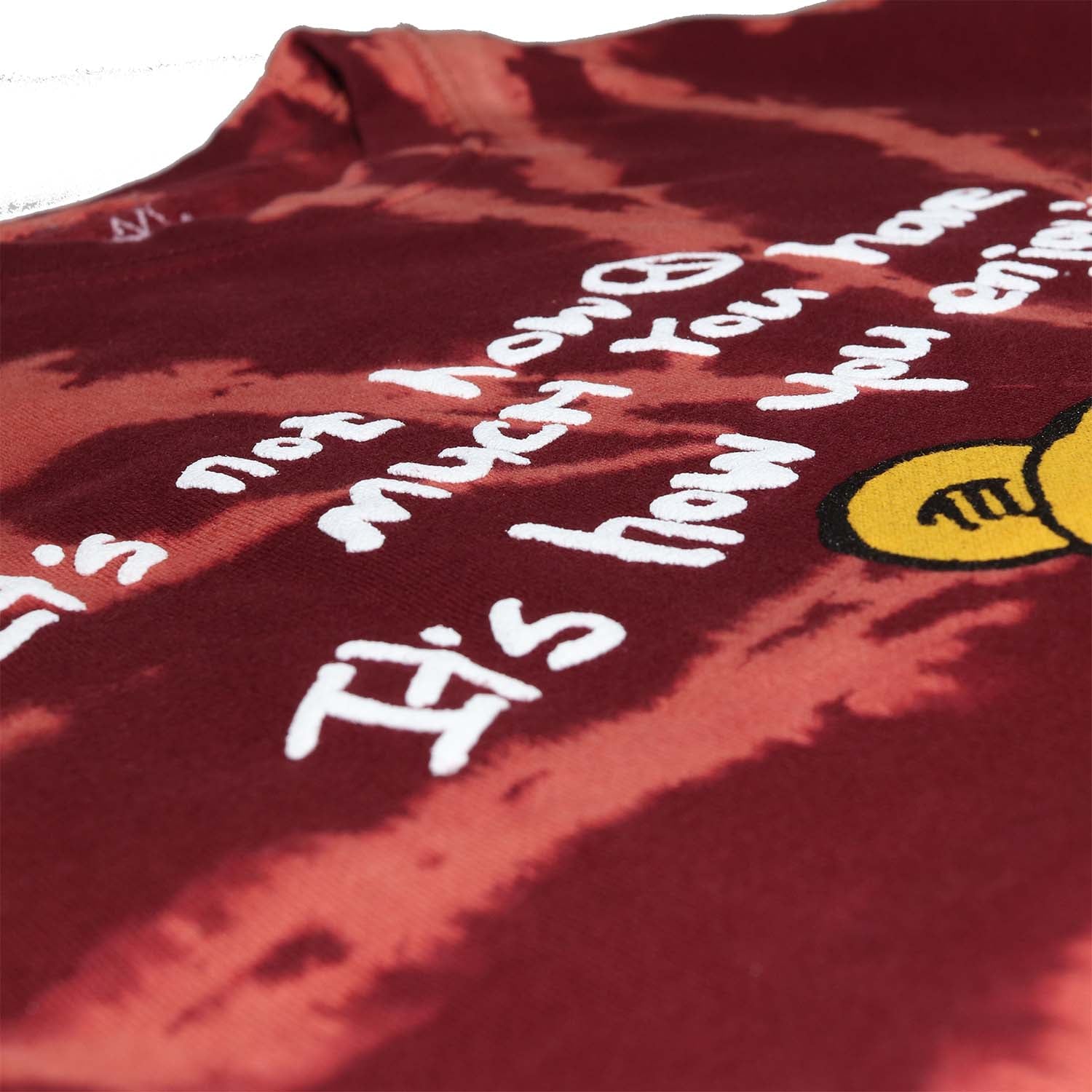 Super closeup photo of puff ink text Teddy Bear sitting with mushrooms graphic printed on front of burgundy tie dye fleece fashion sweatshirt. Graphic includes bear, mushrooms, flower, peace sign and the text "It's not how much you have It's how you enjoy it".