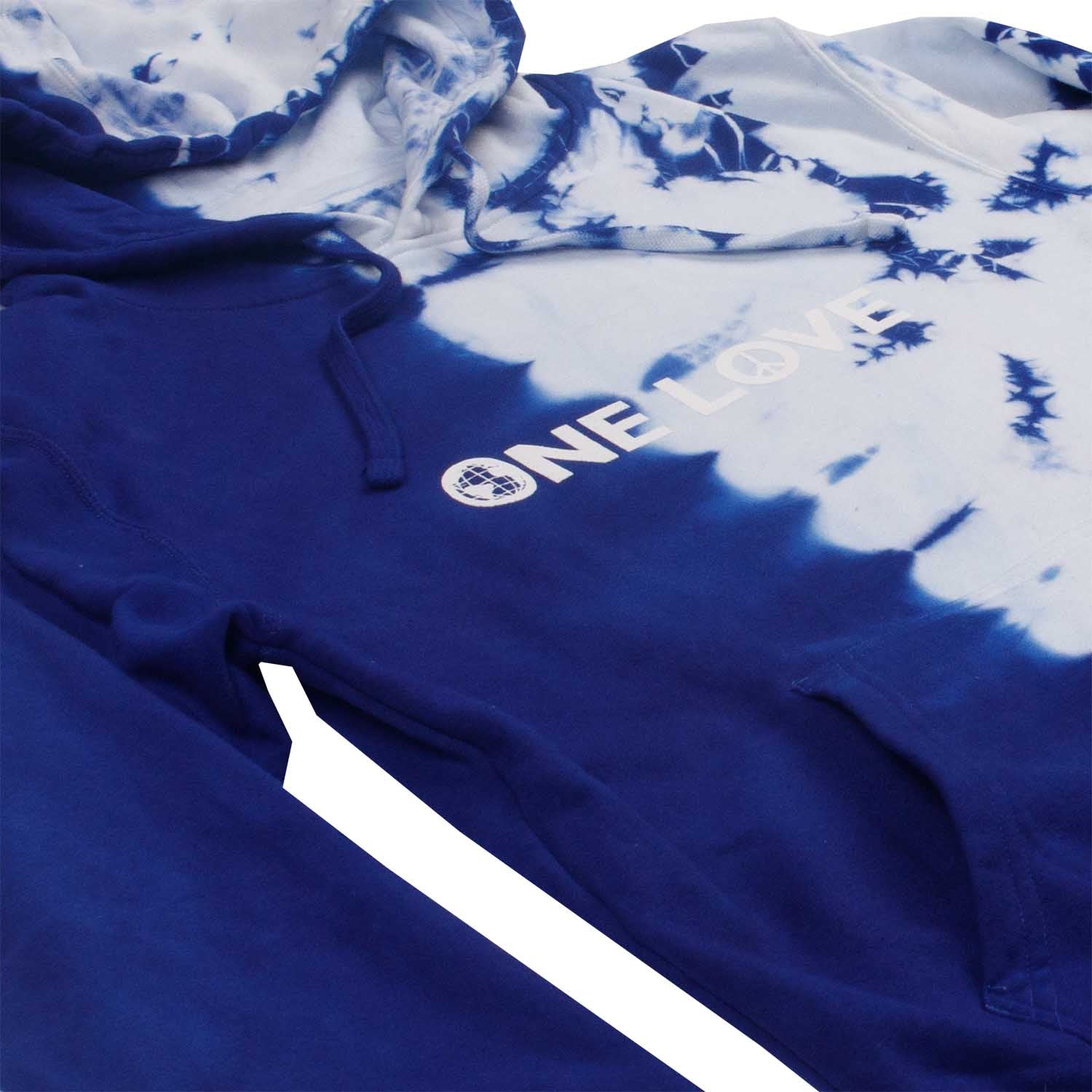 Closeup detail angled photo of text on asymmetrical half tie-dyed blue, white hoodie. The "ONELOVE" text is printed with high density ink.